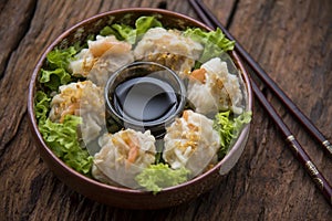 Shumai shrimp with sauce, Steamed shrimp dumplings dim or dim sum and vegetable on wooden table, Cantonese Dimsum food cuisine for