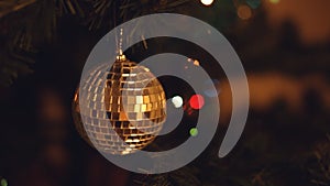 Shuning disco party ball Christmas tree decoration in front of shimmery garland lights. Warm hipster colors and bokeh