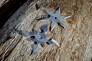 Shuriken throwing star, traditional japanese ninja cold weapon stuck in wooden background