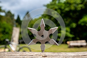 Shuriken throwing star, traditional japanese ninja cold weapon stuck in wooden background