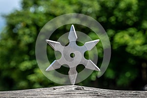 Shuriken throwing star, traditional japanese ninja cold weapon stuck in wooden background
