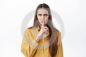 Shush, be quiet. Serious bossy girl hushing, tell to keep mouth shut, taboo gesture, asking for silence, behave yourself