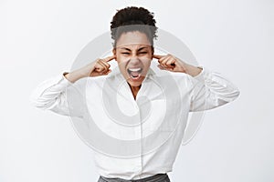 Shut up everybody. Portrait of intense distressed female african-american businesswoman in white shirt, shouting while