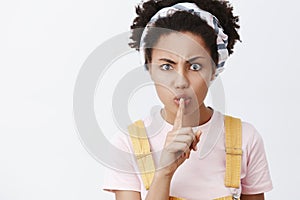 Shut your mouth. Studio shot of strict annoyed African American woman looking dangerious, saying shh while showing shush