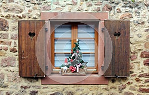 Shutter window with cut out hearts and christmas decorations on the windowsill