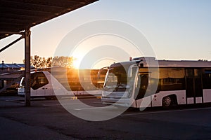 Shuttle buses at the parking lot of the airport in the rays of the setting sun