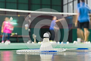 Shuttlecock resting on a badminton racket with badminton player are competiting