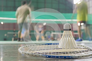 Shuttlecock resting on a badminton racket with badminton player are competiting