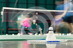 Shuttlecock resting on a badminton racket with badminton player are competiting