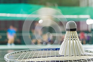 Shuttlecock resting on a badminton racket with badminton player are competiting