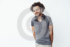 Shy african man with headphones smiling looking down. Copy space. White background.