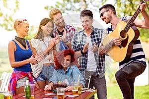 Shy birthday girl with friends who applaud and plays birthday song at guitar