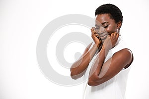 Shy cute african american woman standing and touching her cheeks