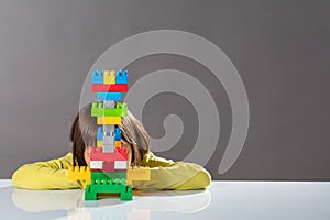 Shy little child hiding behind built toy for kid psychology