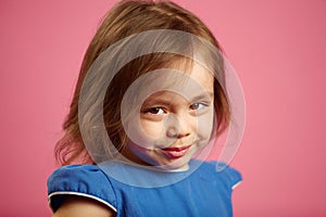 Shy little girl with cute look, close-up portrait on pink isolated background.