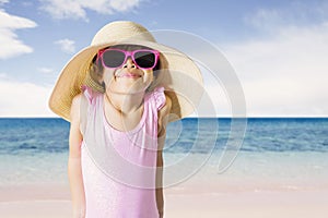 Shy little girl wearing sunglasses on the coast