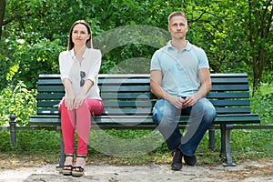 Shy Man And Woman Sitting On Bench