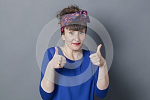 Shy retro 30s woman smiling with two thumbs up