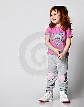Shy smiling cutie smiling little toddler girl in sportswear studio shot