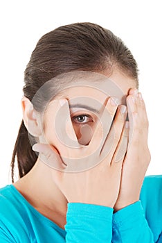 Shy teenage girl peeking through covered face