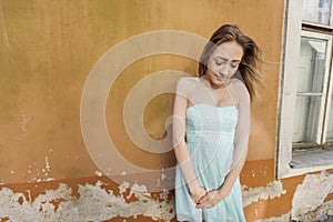Shy teenage girl in tube dress standing against wall