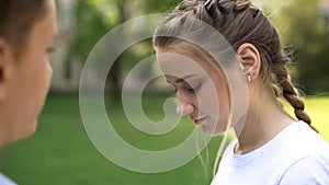 Shy teenager girl looking down, romantic date of students, awkward moment