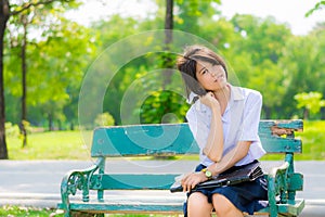 Shy Thai schoolgirl sitting on a bench closeup