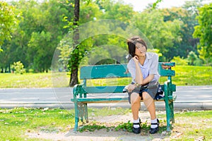 Shy Thai schoolgirl sitting on a bench