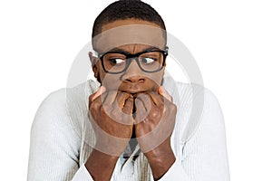 Shy unhappy guy with black glasses biting his nails looking scared