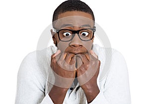 Shy unhappy guy with black glasses biting his nails looking scared