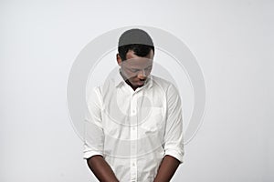 Shy young handsome african man feels awkward isolated on grey wall background.