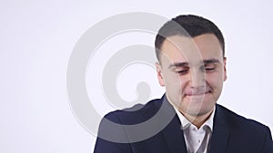 Shy young handsome man smiling, looking at camera over white background