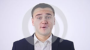 Shy young handsome man smiling, looking at camera over white background