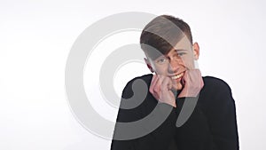 Shy young handsome man smiling, looking at camera over white background