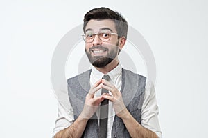 Shy young hispanic man asking for a favor or help smiling. Studio shot