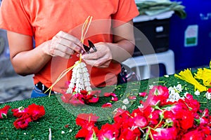 Sian woman staff is stringing flower garlands in flower shop