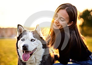 Siberian husky sitting in grass outdoors with th owner girl together - Human and dog friendship and loyalty concept outside on a