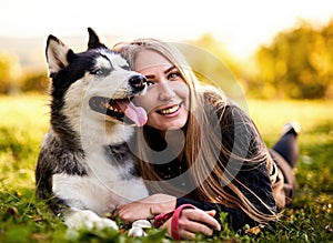 Siberian husky sitting in grass outdoors with th owner girl together - Human and dog friendship and loyalty concept outside on a