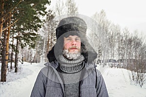 Siberian Russian man with a beard in hoarfrost in freezing cold in the winter freezes and wears a hat with a earflap photo