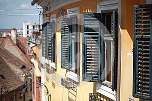 Sibiu yellow building green window with blinds open