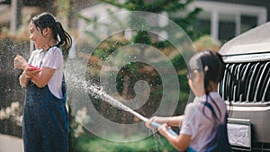 Sibling Asian girls wash their cars and have fun playing indoors on a hot summer day