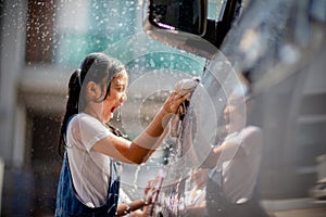 Sibling Asian girls wash their cars and have fun playing indoors on a hot summer day