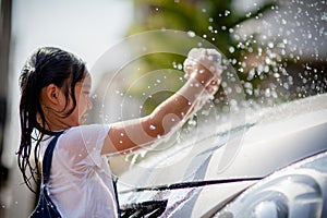 Sibling Asian girls wash their cars and have fun playing indoors on a hot summer day