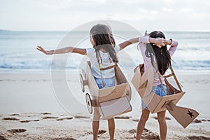 sibling and girl friend playing with cardboard airplane and car on the beach