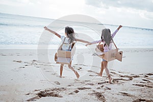 sibling and girl friend playing with cardboard airplane and car on the beach