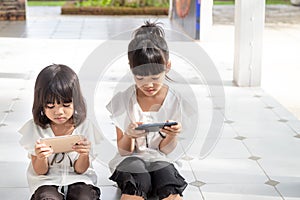 Sibling girls watching their smartphones on white background. Social concept about new technology people addiction