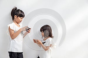 Sibling girls watching their smartphones on white background. Social concept about new technology people addiction