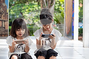 Sibling girls watching their smartphones on white background. Social concept about new technology people addiction