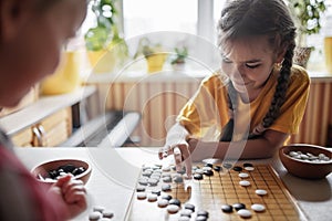 Sibling have fun together playing chess go at home, traditional Chinese board game, digital detox