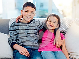 Sibling love at an all time high. Portrait of two adorable young siblings posing with their arms around each other while